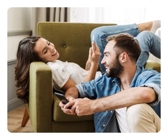 Casal a sorrir e a consultar o telemóvel